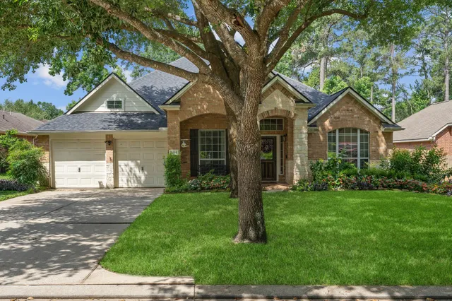 a front view of a house with a yard and large trees