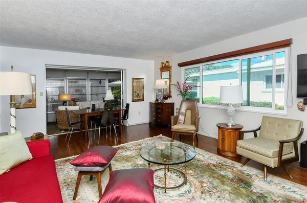 a living room with furniture a wooden floor and next to a window