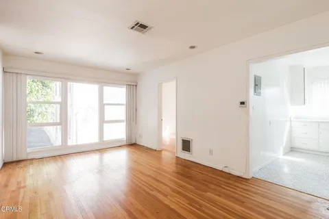 an empty room with wooden floor and windows