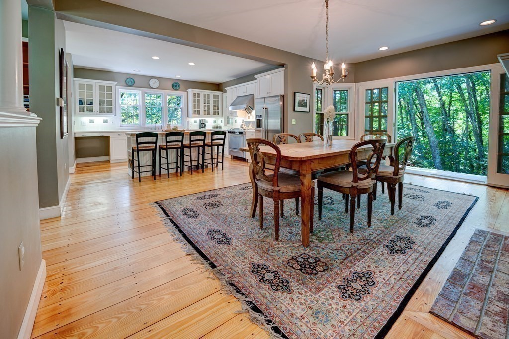 139 Stow Road Harvard, MA 01451 - Photo 12 of 42 a view of a dining room and livingroom with furniture wooden floor a rug a fireplace and a chandelier
