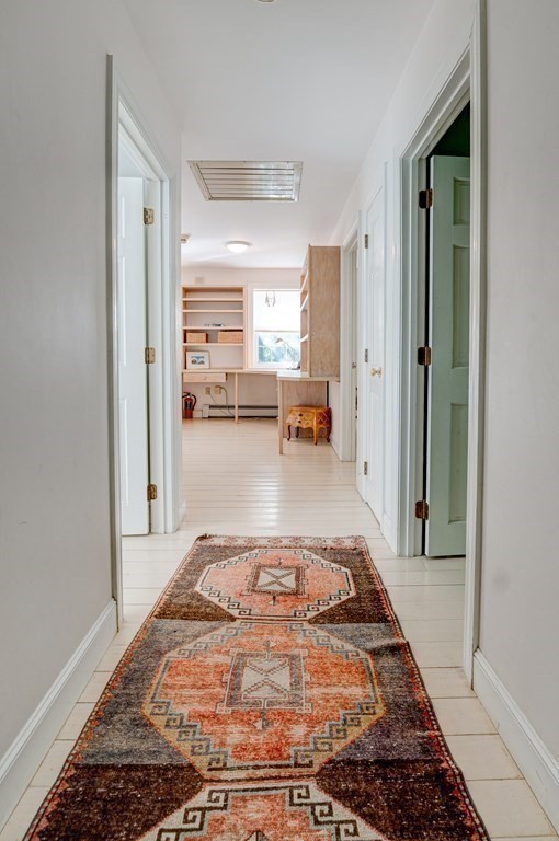 139 Stow Road Harvard, MA 01451 - Photo 23 of 42 a view of a hallway to a livingroom with wooden floor and a rug