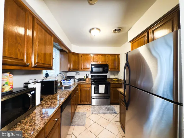 a kitchen with stainless steel appliances granite countertop a refrigerator a stove top oven and sink