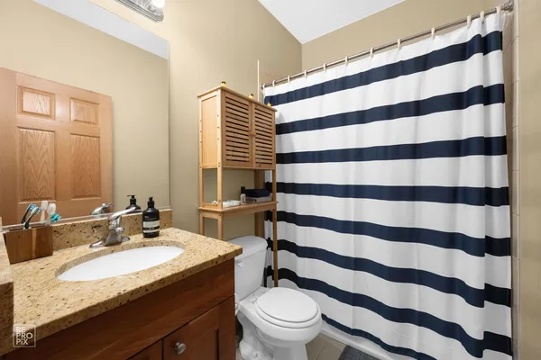 a bathroom with a granite countertop sink a toilet a mirror and shower curtain