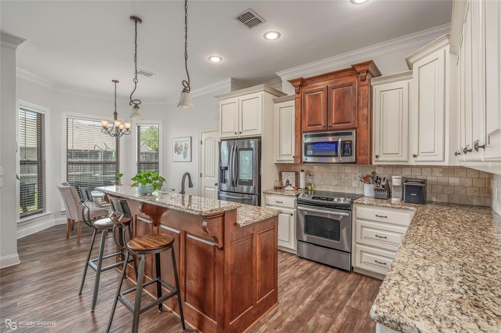 711 Reeds Reef Bossier City, LA 71112 - Photo 14 of 36 a kitchen with stainless steel appliances granite countertop a stove top oven a sink dishwasher a dining table and chairs with wooden floor