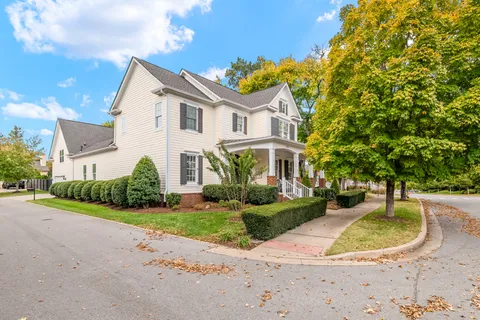 a view of a white house with a yard and table and chairs next to yard