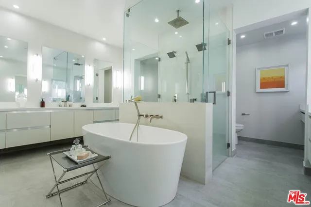 a bathroom with a tub a sink a mirror and a shower