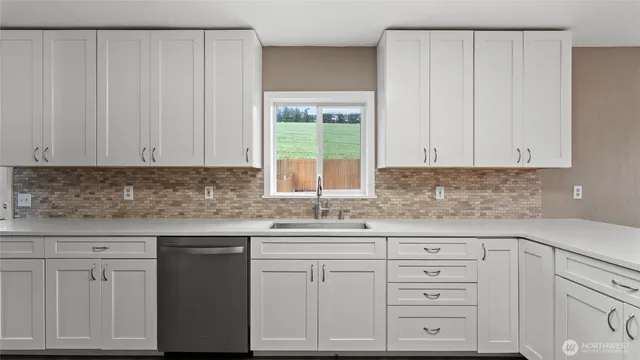 a kitchen with white cabinets and sink