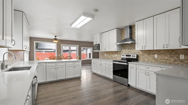a kitchen with a white cabinets stove and wooden floor