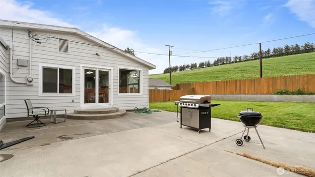 a backyard of a house with barbeque oven table and chairs