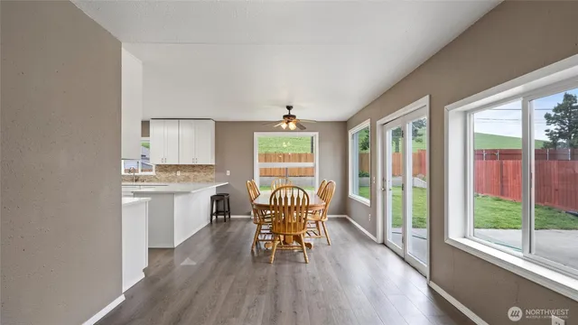 a dining room with wooden floor a chandelier a glass table and chairs