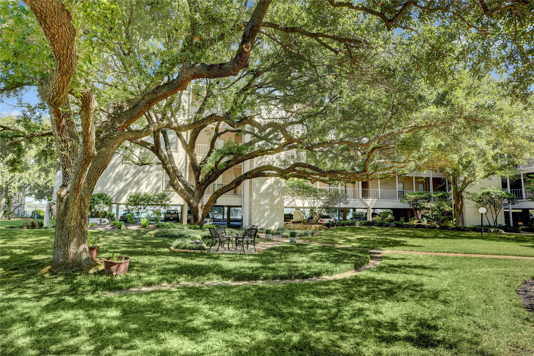 351 Lakeside Lane, Unit 102 Houston, TX 77058 - Photo 13 of 14 a backyard of a house with large trees and outdoor seating