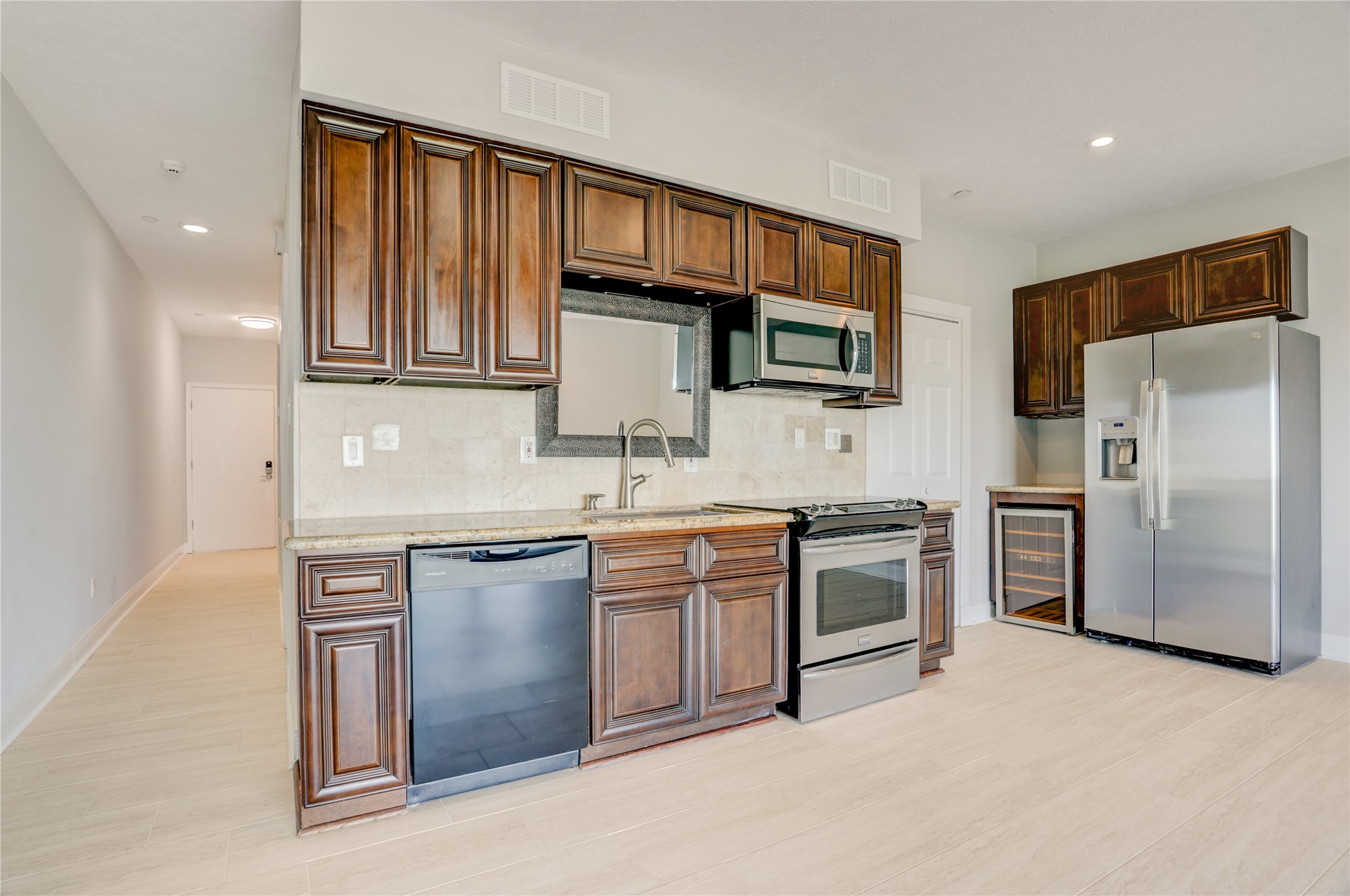 351 Lakeside Lane, Unit 102 Houston, TX 77058 - Photo 6 of 14 a kitchen with stainless steel appliances granite countertop a stove top oven a sink and dishwasher a refrigerator with wooden cabinets