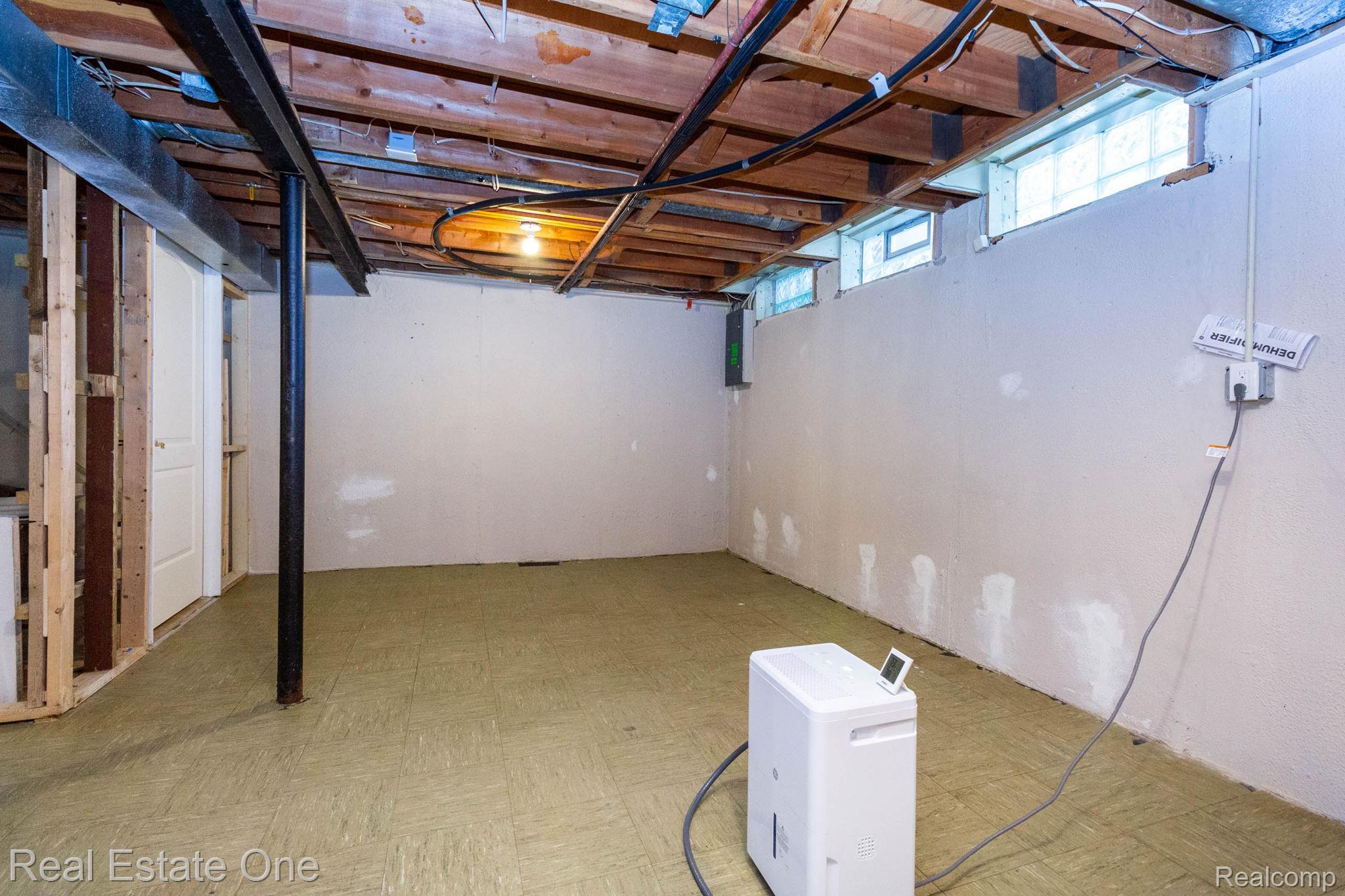111 Manor Way Rochester, MI 48309 - Photo 28 of 36 Basement space featuring exposed wooden ceiling joists, concrete block walls, and multiple glass block windows