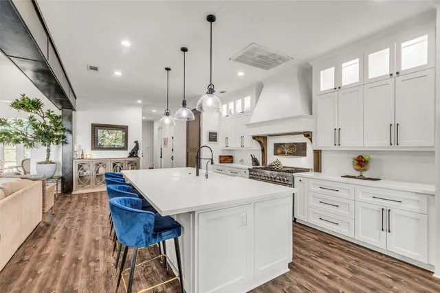 a large kitchen with sink a microwave oven a stove and white cabinets