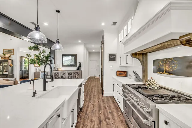 a kitchen with stainless steel appliances granite countertop a sink a stove and a wooden floors