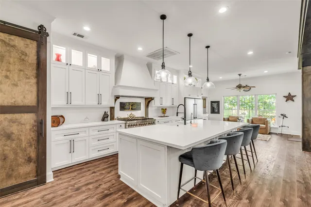 a large kitchen with kitchen island a island a sink a stove and a wooden floor