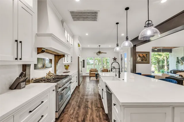 a kitchen with stainless steel appliances granite countertop a stove a sink dishwasher a refrigerator oven a dining table and chairs with wooden floor