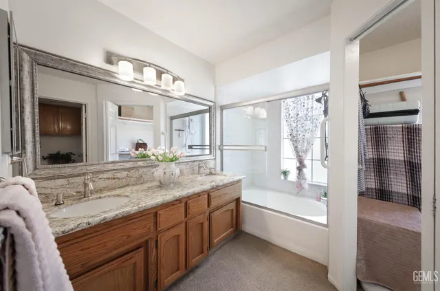 a bathroom with a granite countertop tub sink double vanity and a large mirror