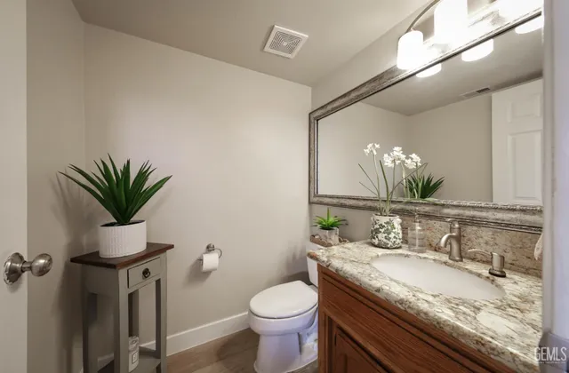 a bathroom with a granite countertop sink a toilet and a mirror