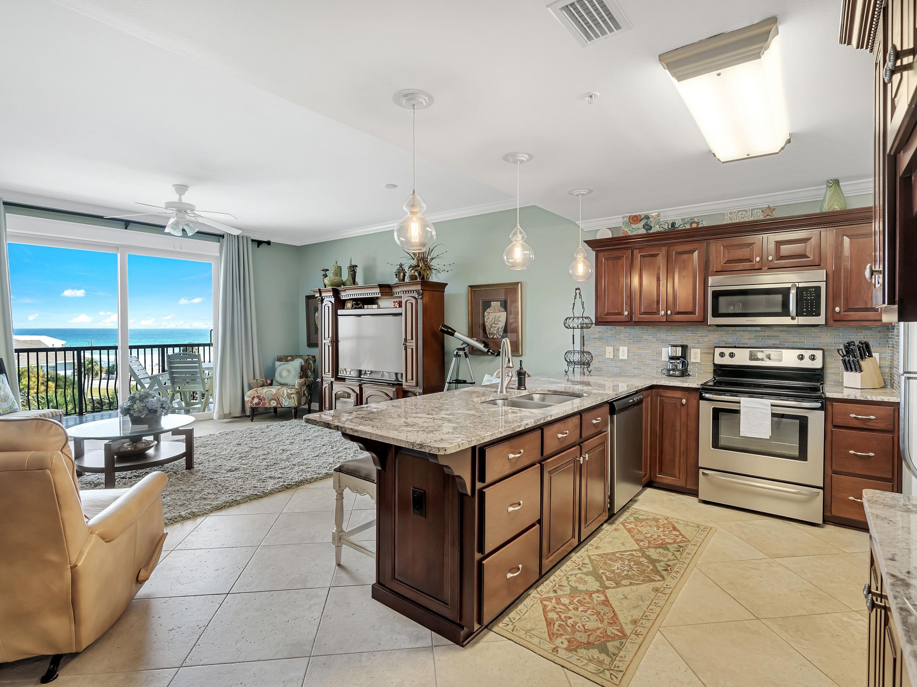 548 Sandy Cay Drive, Unit 510 Miramar Beach, FL 32550 - Photo 3 of 30 a kitchen with stainless steel appliances granite countertop a stove top oven a sink dishwasher a dining table and chairs with wooden floor