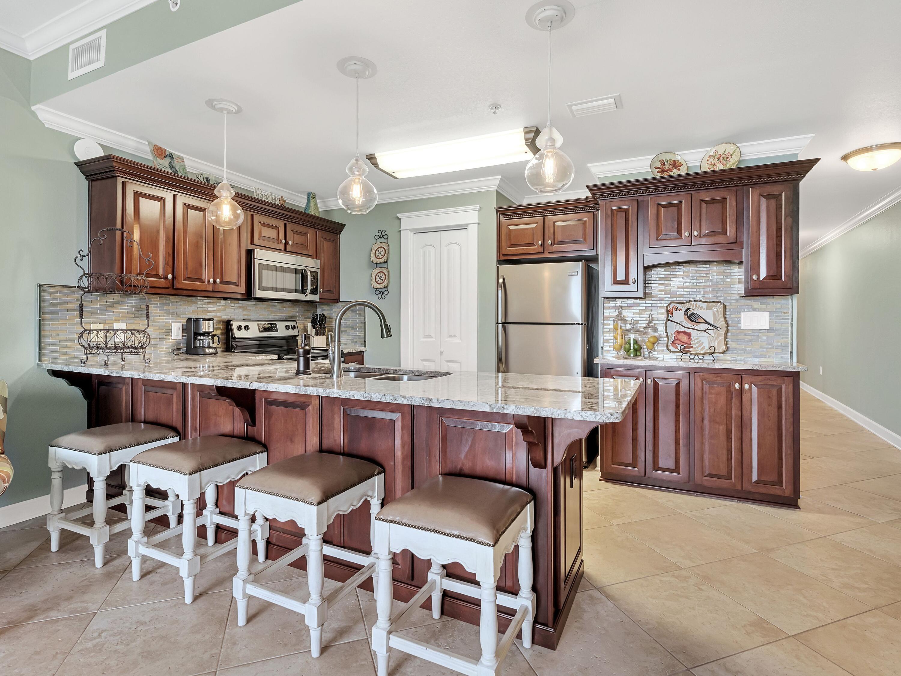 548 Sandy Cay Drive, Unit 510 Miramar Beach, FL 32550 - Photo 9 of 30 a dining area with stainless steel appliances granite countertop a kitchen island a stove a table and chairs