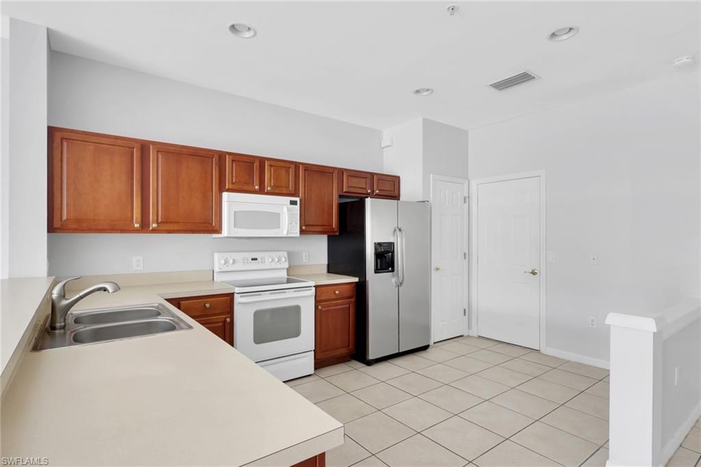 937 Hampton Circle, Unit 108 Naples, FL 34105 - Photo 4 of 32 a kitchen with stainless steel appliances granite countertop a refrigerator sink and stove