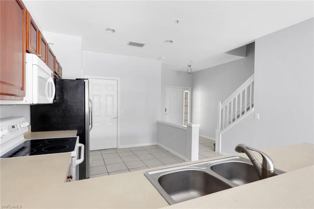937 Hampton Circle, Unit 108 Naples, FL 34105 - Photo 6 of 32 a kitchen with a sink and a refrigerator