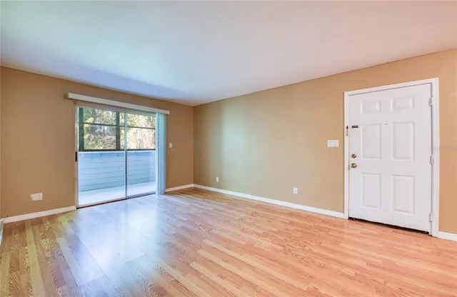 a view of an empty room with wooden floor and a window