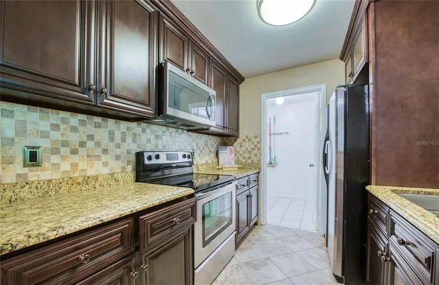 a kitchen with stainless steel appliances granite countertop a refrigerator a stove and a sink