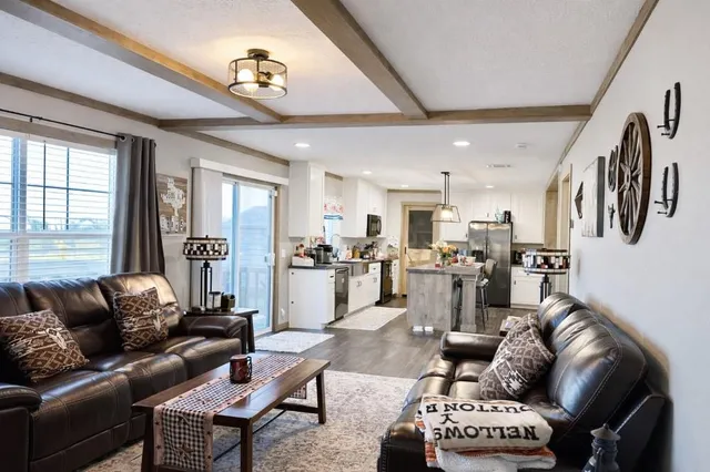 a living room with furniture kitchen view and a large window