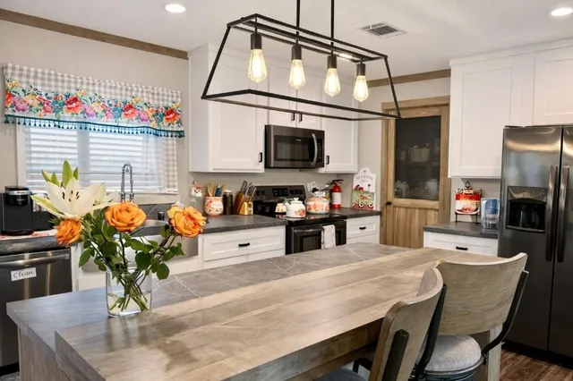 a kitchen with stainless steel appliances kitchen island granite countertop a table chairs in it and wooden floors