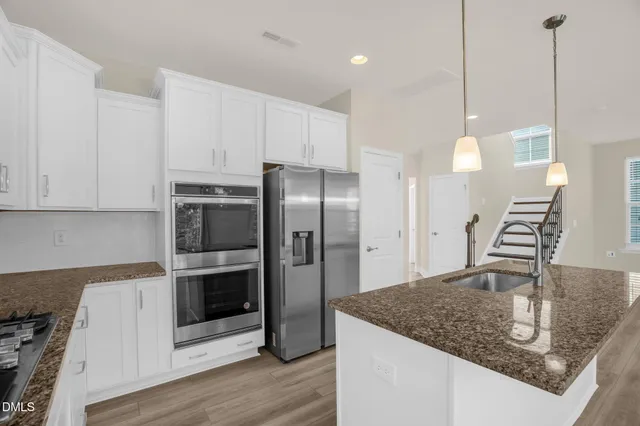 a large kitchen with cabinets wooden floor and stainless steel appliances