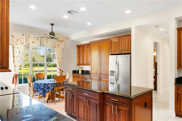 a view of a kitchen with kitchen island granite countertop a large window and stainless steel appliances