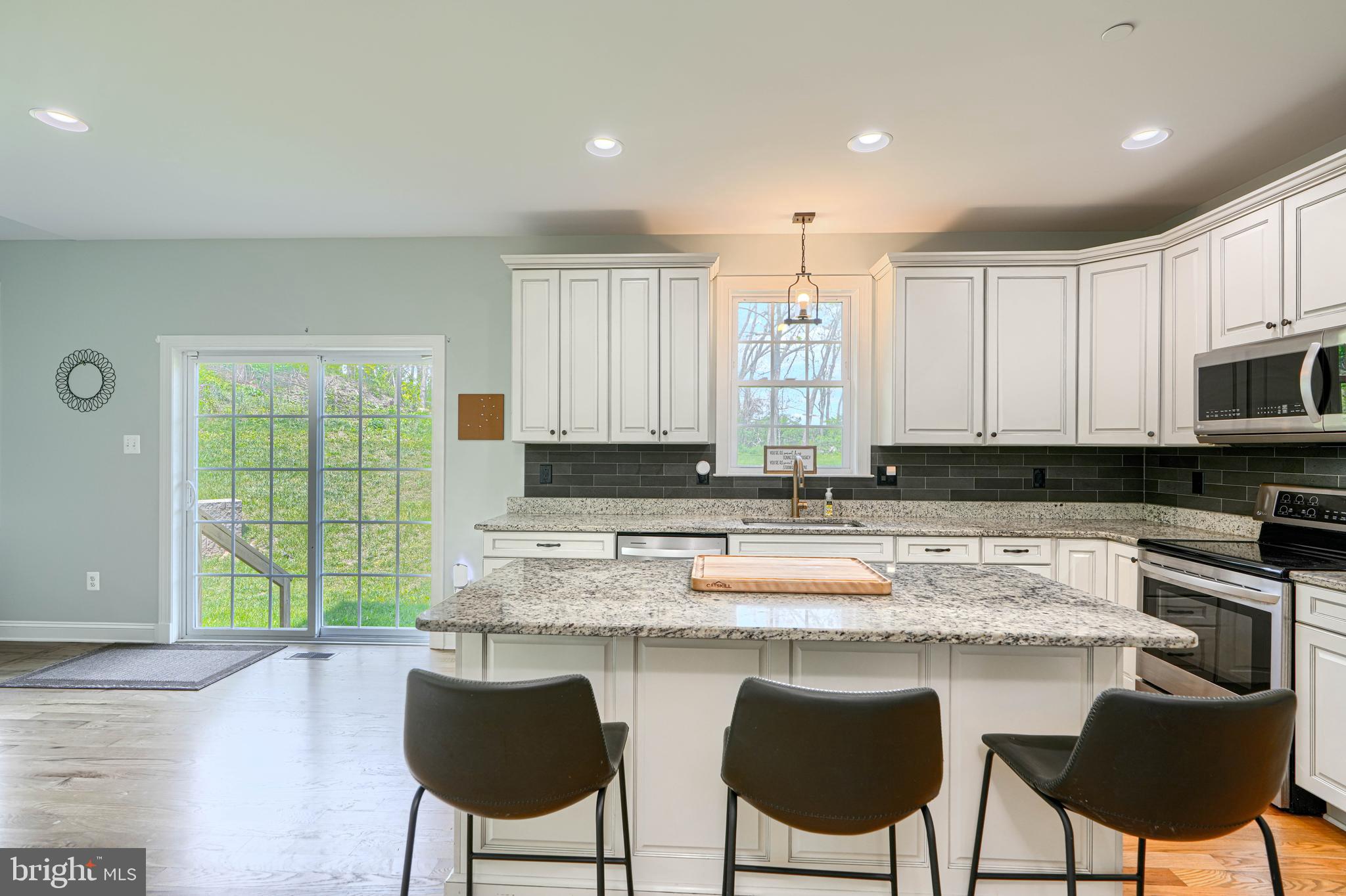 13012 Liberty Road Union Bridge, MD 21791 - Photo 14 of 47 a kitchen with stainless steel appliances granite countertop a stove top oven a sink dishwasher and chairs with wooden floor