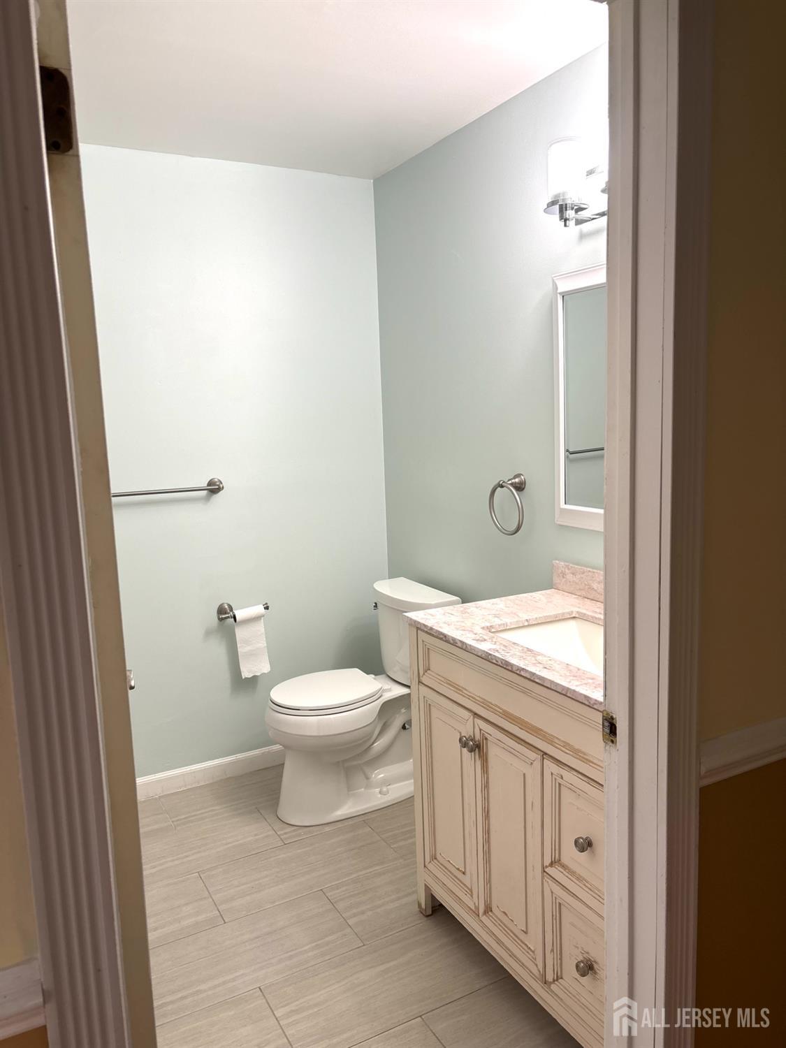 98 Keystone Court Edison, NJ 08817 - Photo 9 of 13 a bathroom with a granite countertop toilet a sink and a mirror