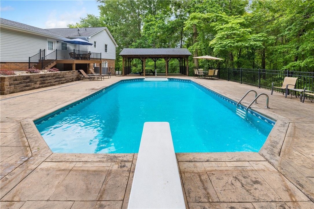 404 South Old Mill Road Seneca, SC 29678 - Photo 26 of 39 An inviting swimming pool surrounded by spacious concrete decking sits adjacent to mature woodland trees.