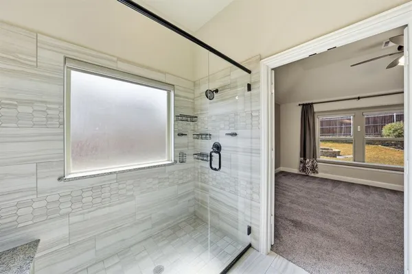 a bathroom with a glass shower door and a window