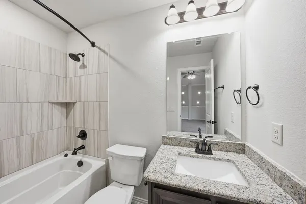 a bathroom with a granite countertop sink mirror and a bathtub