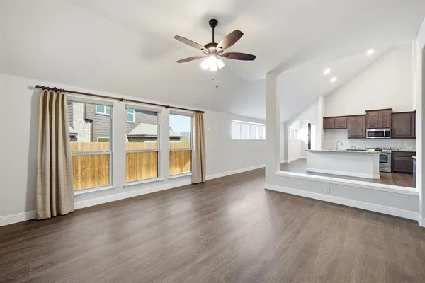 a view of an empty room with a kitchen and wooden floor