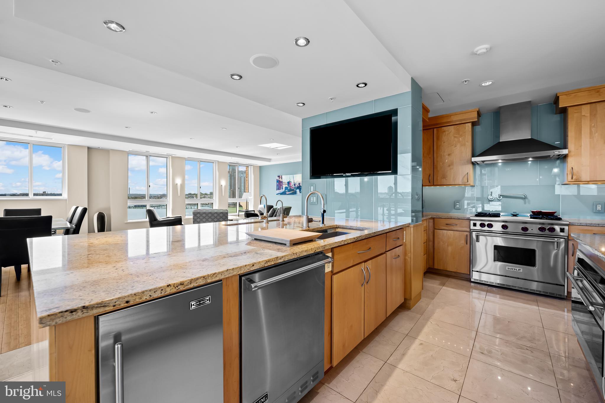 717 President Street, Unit PH802 Baltimore, MD 21202 - Photo 14 of 77 a large kitchen with stainless steel appliances granite countertop a stove top oven a sink dishwasher and white cabinets with wooden floor