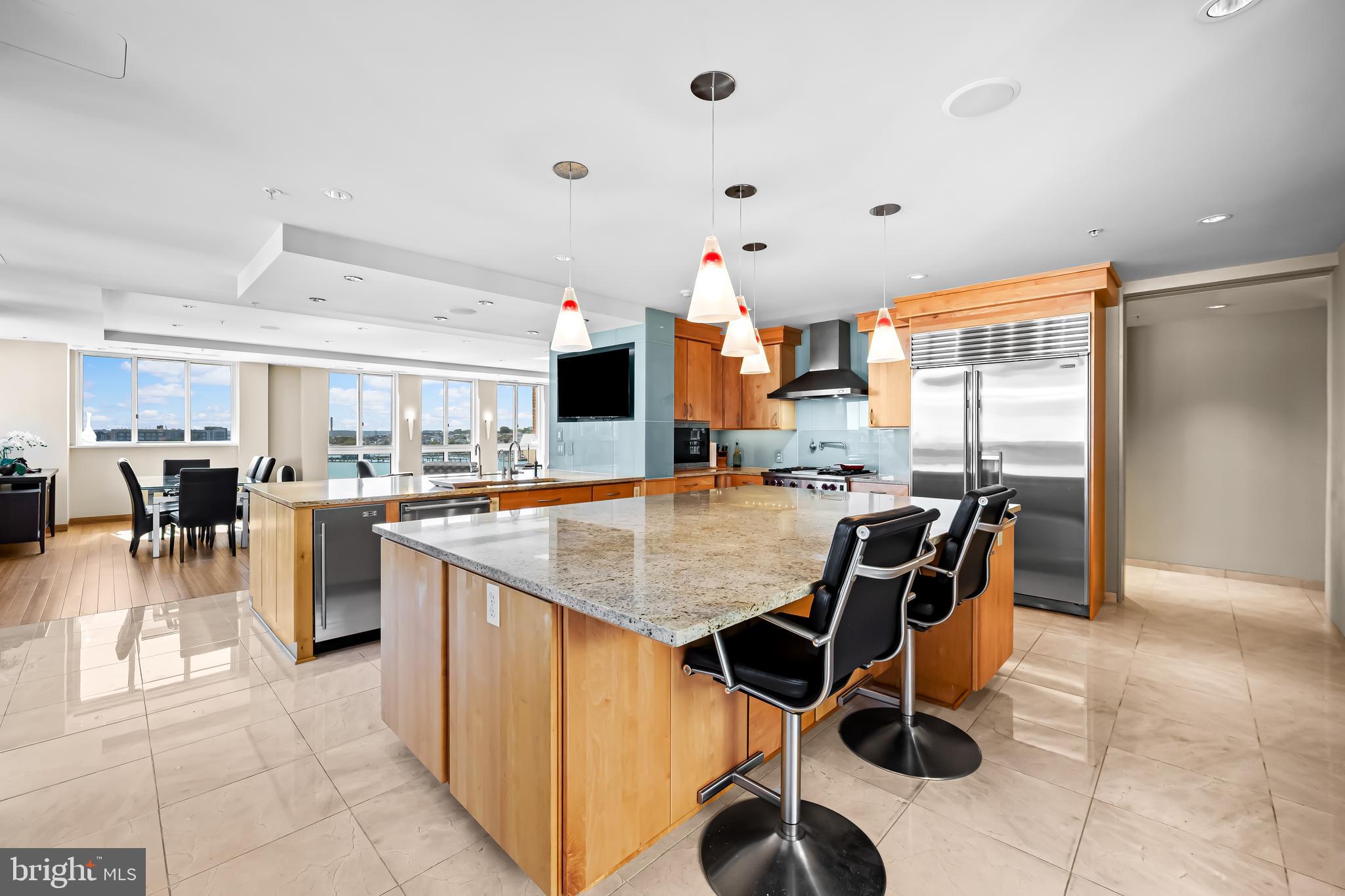 717 President Street, Unit PH802 Baltimore, MD 21202 - Photo 15 of 77 a open kitchen with stainless steel appliances kitchen island granite countertop a table chairs and a refrigerator