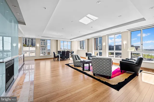 a large kitchen with stainless steel appliances granite countertop a stove top oven a sink dishwasher and white cabinets with wooden floor