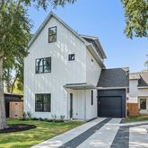 a front view of a house with a yard and large tree