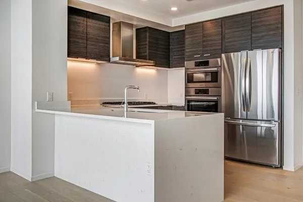 a dining hall with stainless steel appliances granite countertop a sink and dishwasher with wooden floor