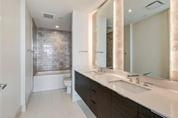 a bathroom with a double vanity sink toilet mirror and bathtub