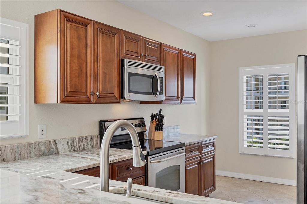 8413 Placida Road, Unit 308 Placida, FL 33946 - Photo 11 of 40 a kitchen with stainless steel appliances granite countertop a stove a sink and a microwave