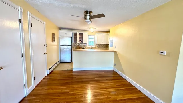 a view of a kitchen with wooden floor and a ceiling fan