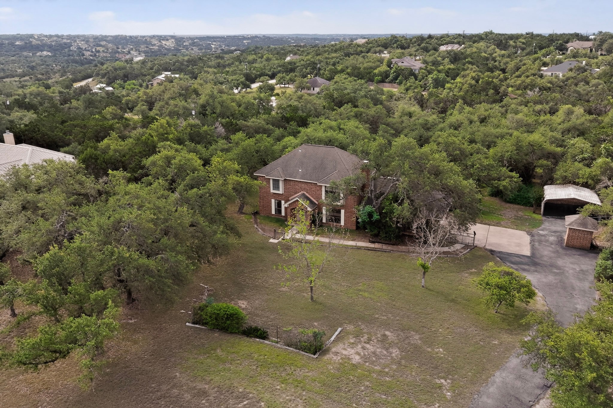1003 Pier Branch Road Dripping Springs, TX 78620 - Photo 7 of 40 A secluded brick residence nestled among a lush canopy of mature trees, offering a private retreat.
