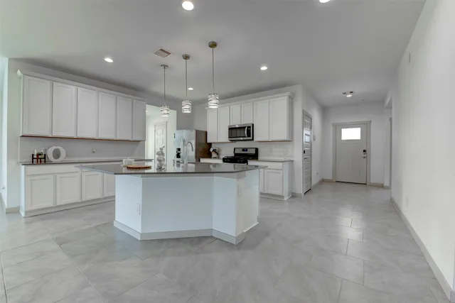 a kitchen with kitchen island granite countertop a sink a counter top space appliances and cabinets