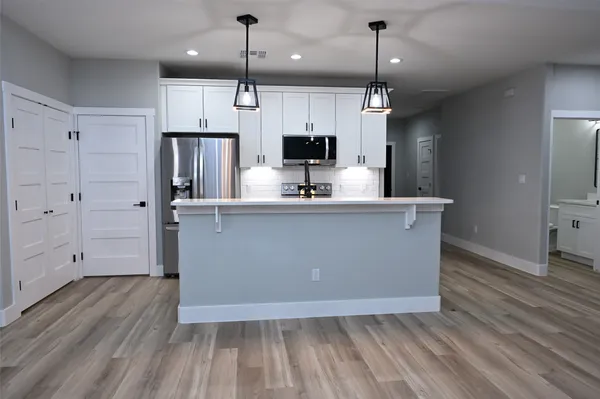 a kitchen with kitchen island a counter top space a sink a refrigerator and a fireplace